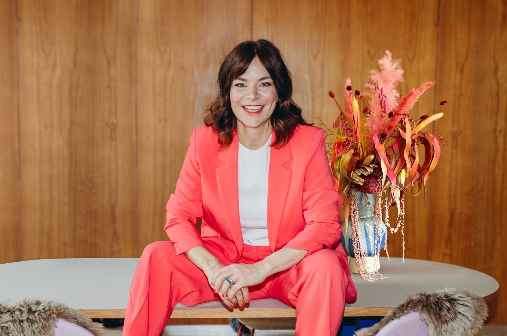 Katrin Moritz sitzt fröhlich auf einem Tisch